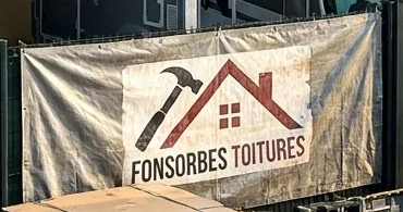 Bâche Fonsorbes Toitures accrochée à la clôture pendant un chantier de couverture à Fonsorbes